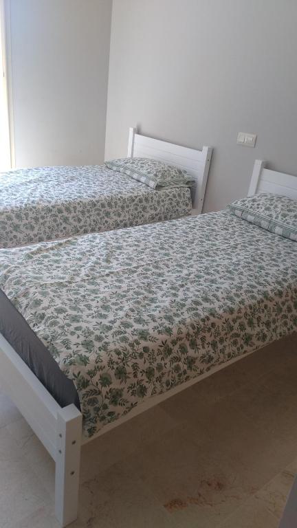 two beds sitting next to each other in a room at Résidence avec piscine Kenz Mehdia in Kenitra