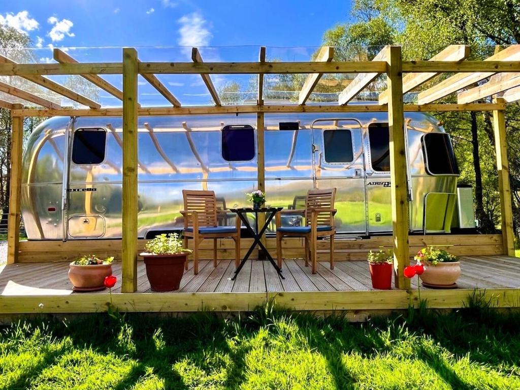 eine Terrasse mit Stühlen und einem Tisch vor einem Wohnwagen in der Unterkunft Bonny Airstream in Inver Mallie