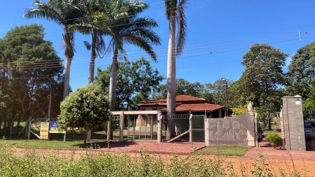 a building with a gate and palm trees at Villa Domus in Barretos