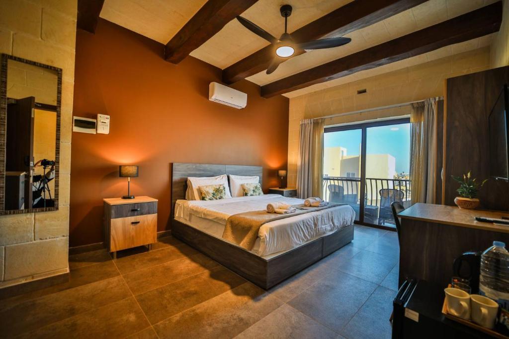 a bedroom with a large bed and a balcony at 49 Sunrise Lodge in Għajnsielem