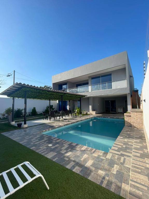 a house with a swimming pool in front of it at Villa Matthew - Villa de Lujo con Piscina Privada y BBQ, Cerca al Mar in Juan de Acosta