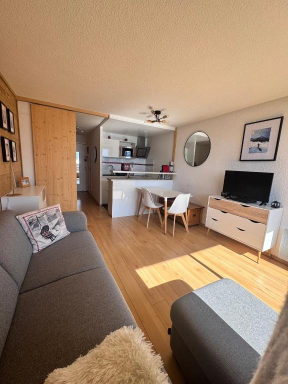 un salon avec un canapé et une table avec une télévision dans l'établissement Tout schuss au Panoramic, à Orcières