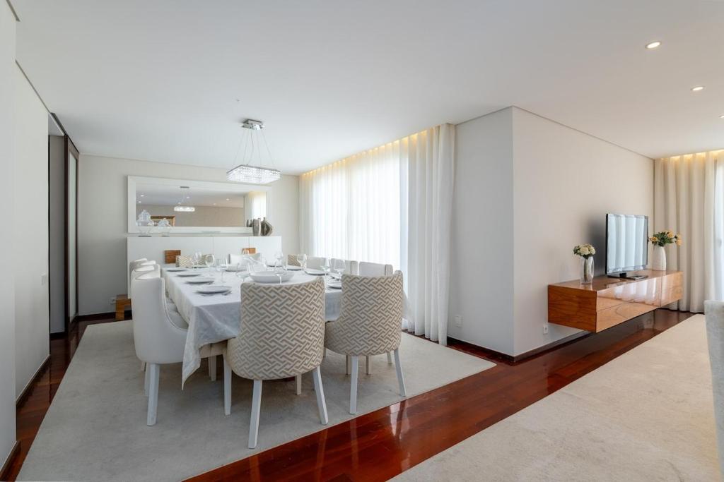 uma sala de jantar com uma mesa e cadeiras brancas em The Povoa Villa na Póvoa do Varzim