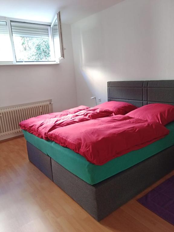 ein Schlafzimmer mit einem Bett mit roter Bettwäsche und einem Fenster in der Unterkunft Bei EDE & Helli in Klotten