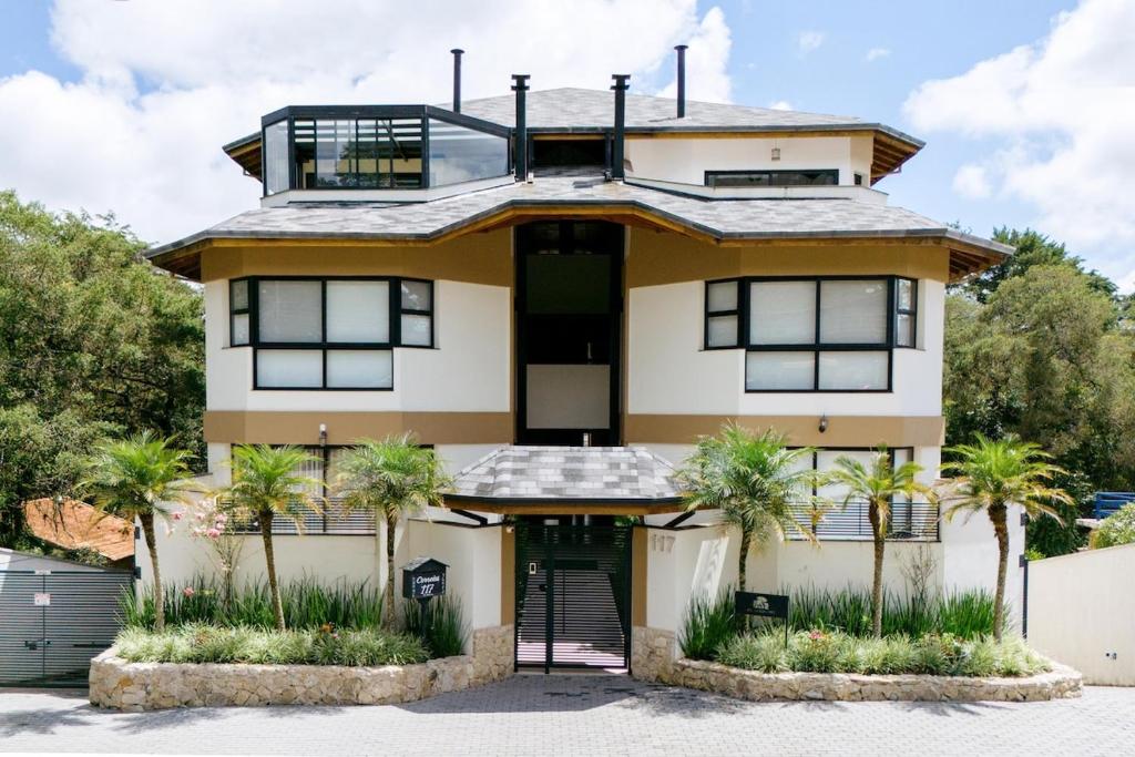 a house with palm trees in front of it at Apartamento Le Neuf Centro in Monte Verde
