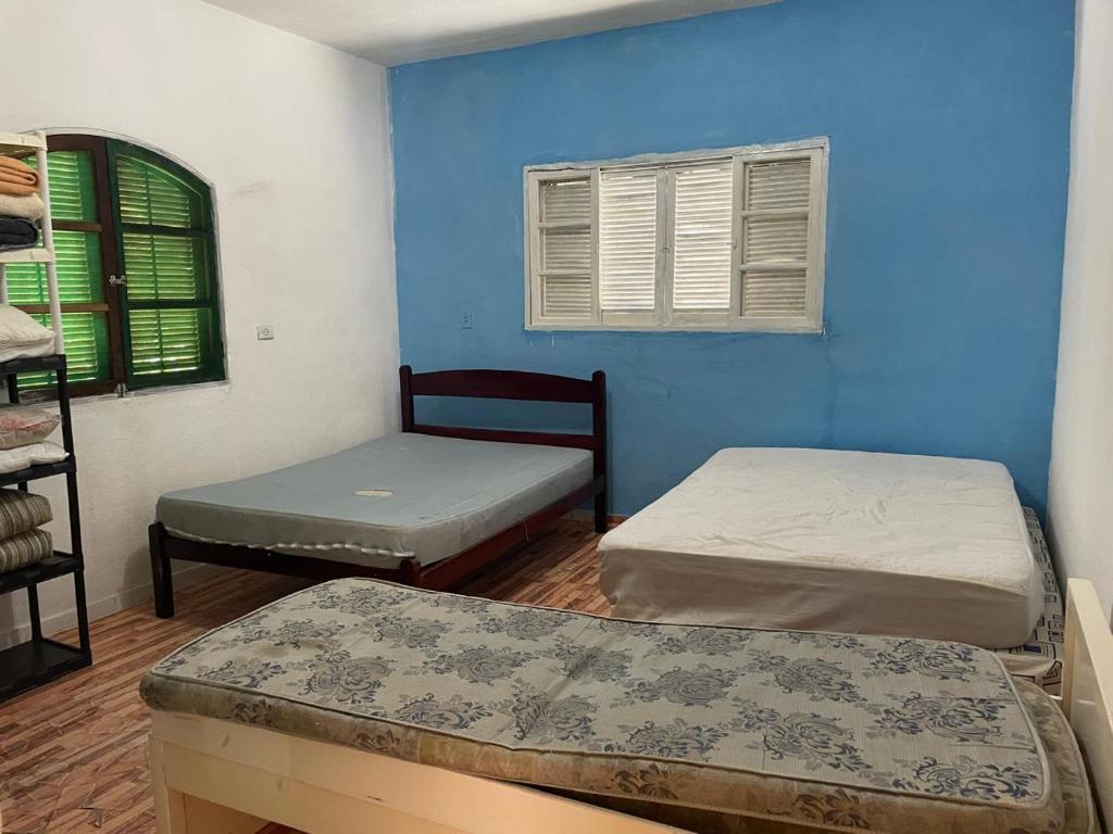 ein Zimmer mit zwei Betten und einer blauen Wand in der Unterkunft Cantinho da serra do Guaraú in Peruíbe