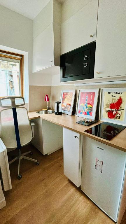 - une cuisine avec un bureau, une chaise et un four micro-ondes dans l'établissement Studio neuf, à Paris