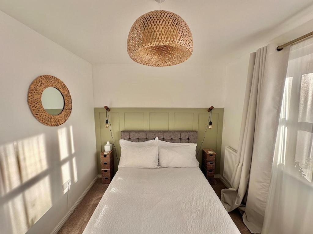 a bedroom with a large bed with white sheets and a mirror at Lovely 2 bedroom home in Enham-Alamein