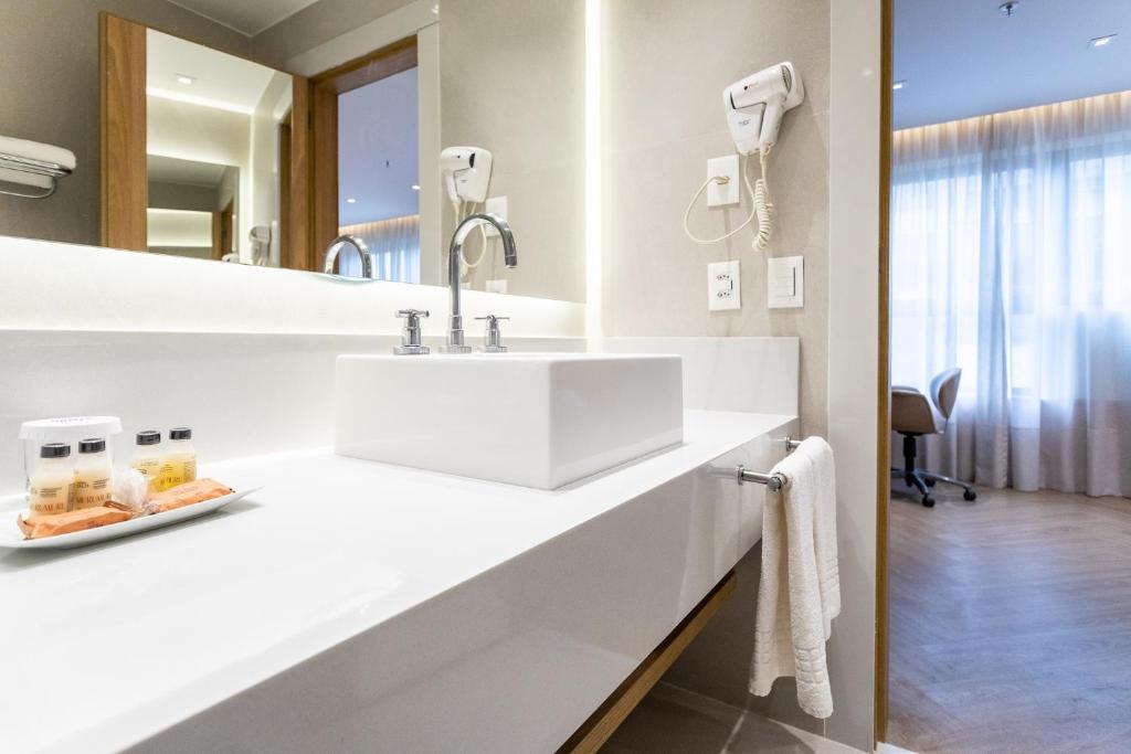 a white bathroom with a sink and a mirror at Mar Ipanema Hotel in Rio de Janeiro