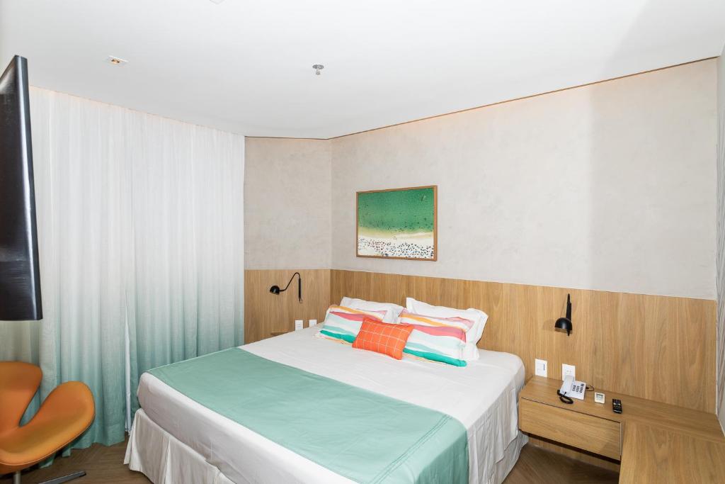 a bedroom with a bed and a chair and a television at Mar Ipanema Hotel in Rio de Janeiro