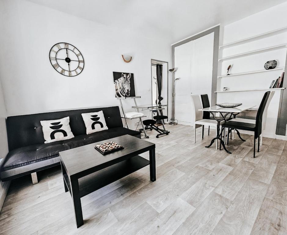 un salon avec un canapé noir et une table dans l'établissement Henri, Hyper centre, Parking privé, à Reims
