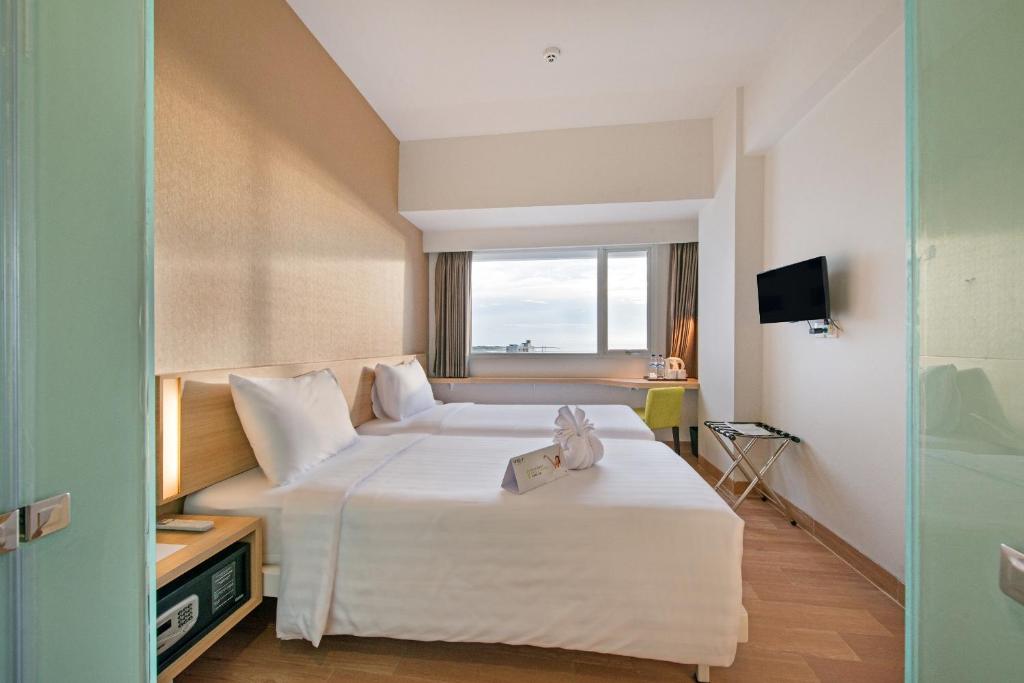 Postel nebo postele na pokoji v ubytování Whiz Prime Hotel Hasanuddin Makassar