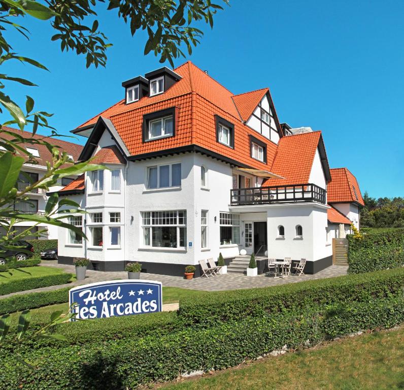 ein großes weißes Haus mit orangefarbenem Dach in der Unterkunft Hotel Les Arcades in Knokke-Heist