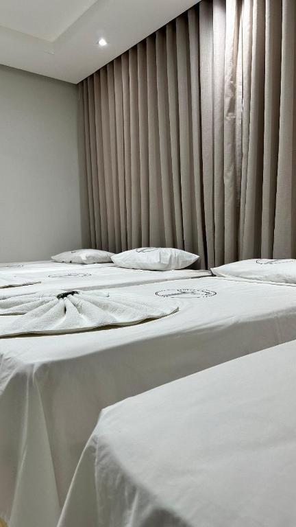 a row of white beds in a room at Hotel Castanhal in Castanhal