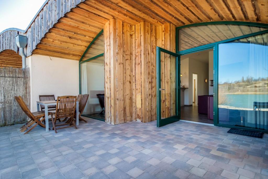 a patio with a table and chairs and a glass door at LAGOVIDA Dünenhaus Comfort Familia f am Störmthaler See in Großpösna