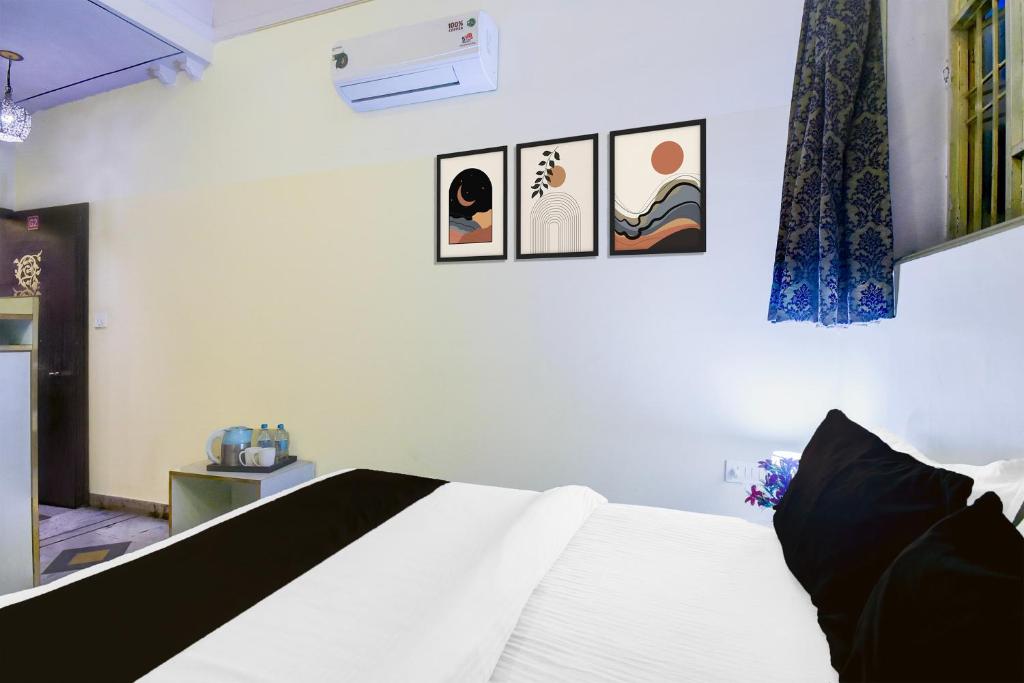 a bedroom with a white bed and three pictures on the wall at Super Hotel O Sikar Road Jaipur Formerly Garg Niwas in Jaipur