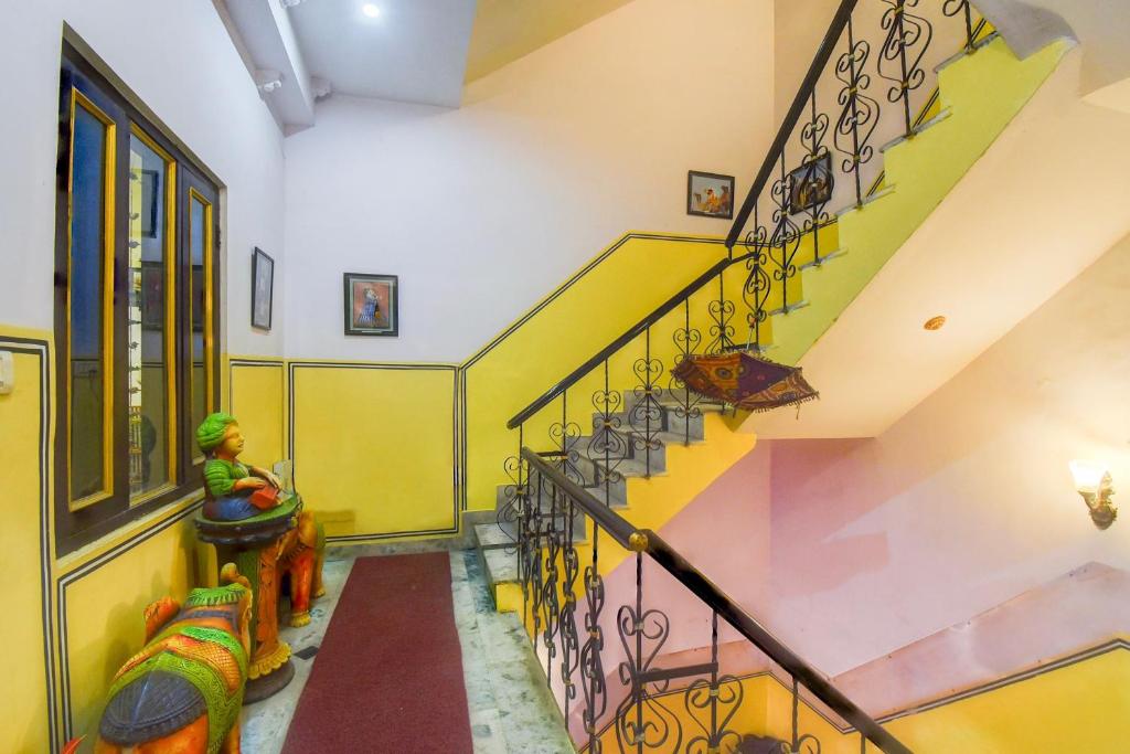 a hallway with a staircase with yellow and green walls at Super Hotel O Sikar Road Jaipur Formerly Garg Niwas in Jaipur