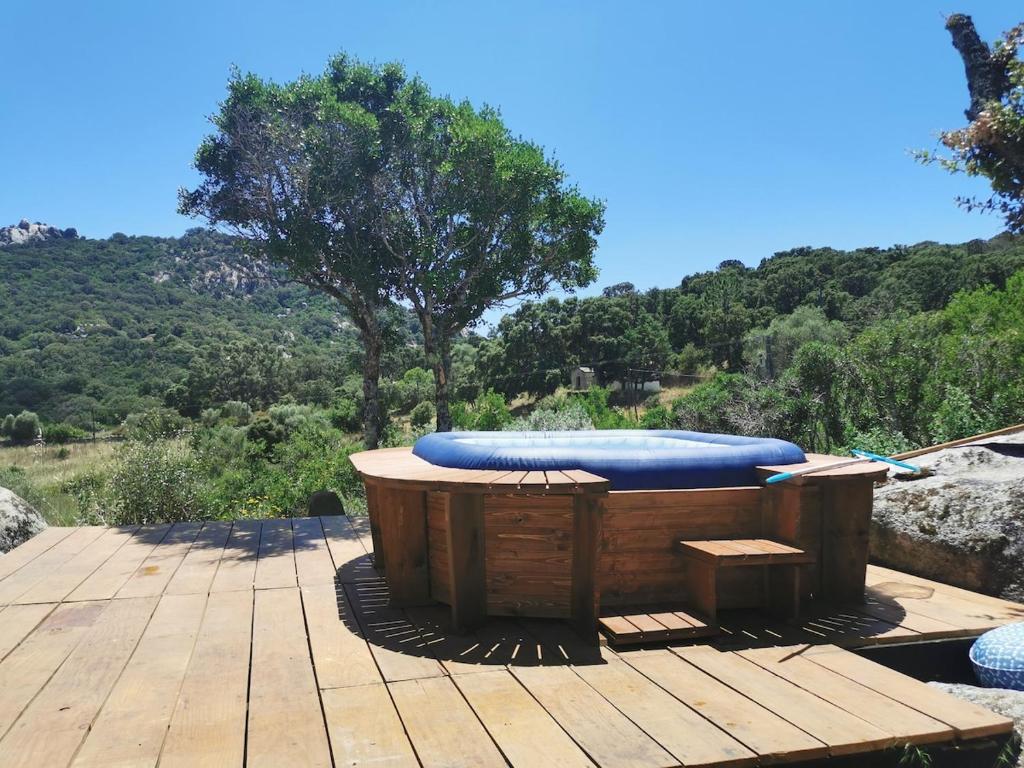 un bain à remous en bois avec un radeau bleu assis sur une terrasse en bois dans l'établissement Maison de campagne idéale pour séjour en famille, à Porto-Vecchio