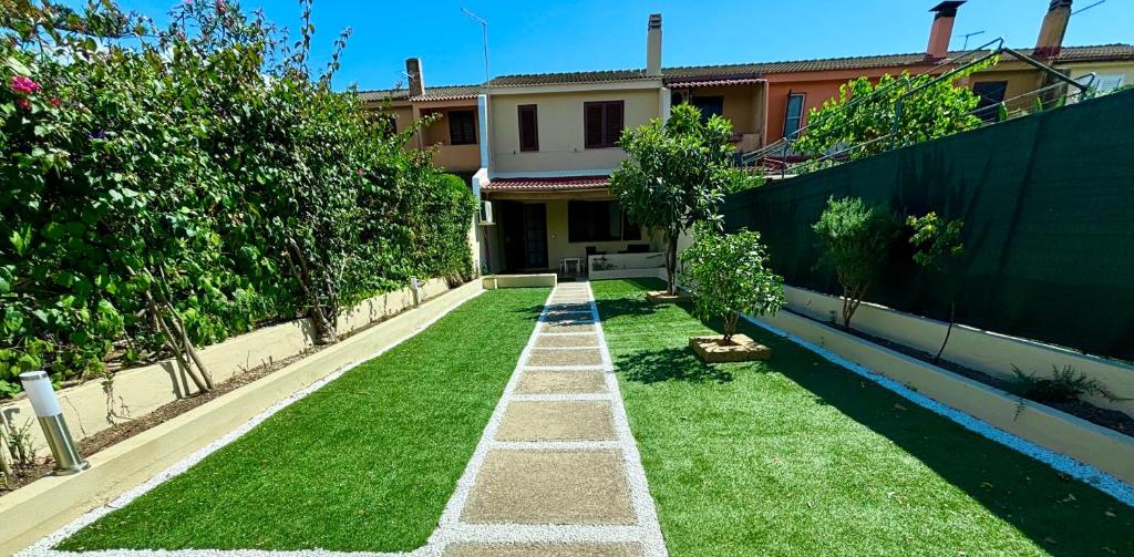 un giardino con prato e alberi di fronte a una casa di Domu e Mari Sud Sardegna a Quartu SantʼElena