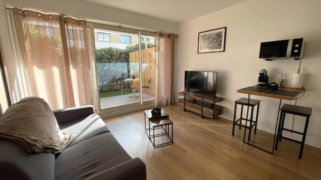 un salon avec un canapé et une télévision dans l'établissement Studio proche plage avec jardinet et parking - Casa Garcia, à Villeneuve-Loubet