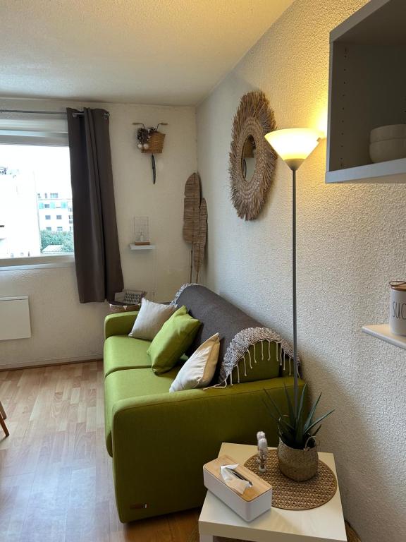 un salon avec un canapé vert et une table dans l'établissement Studio - Calais la Plage, à Calais