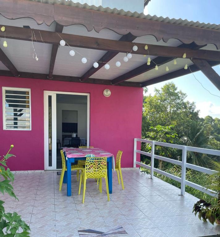 a patio with a table and chairs and a pink wall at colibris Location SAINTE-ANNE in Sainte-Anne