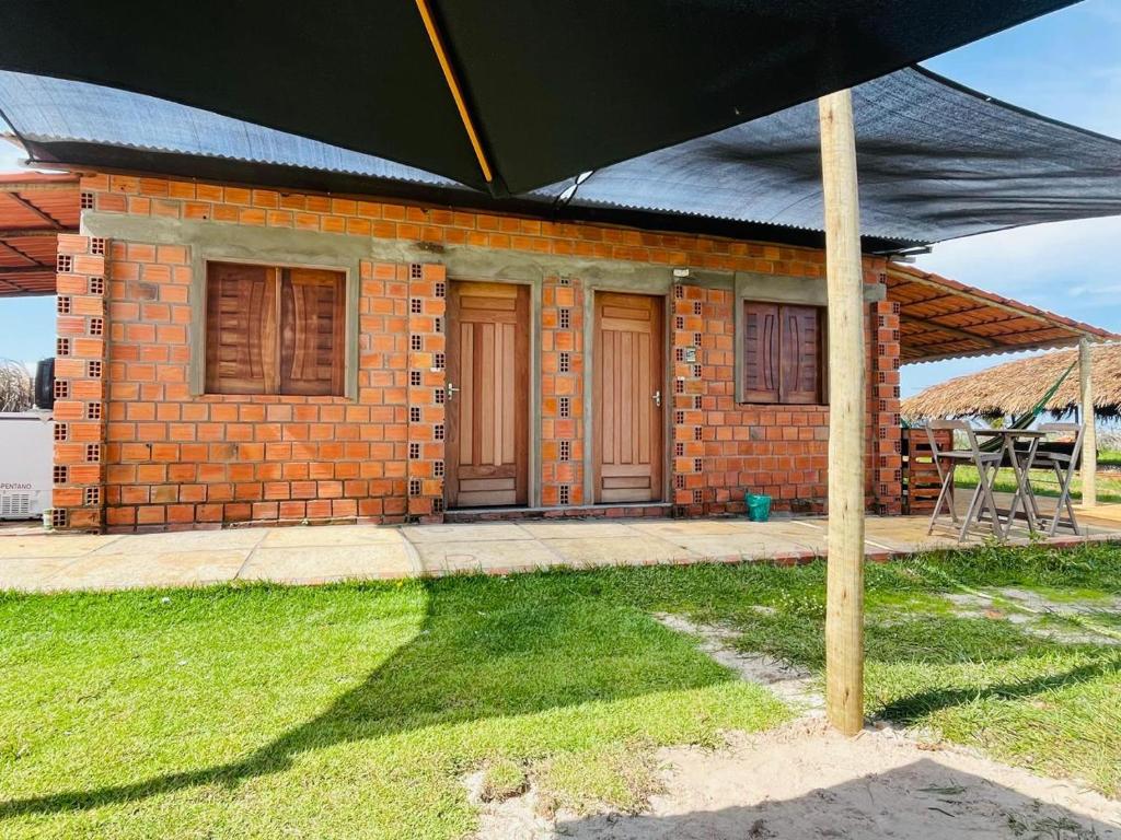 a brick house with a black umbrella in front of it at Villa Lençóis in Barreirinhas