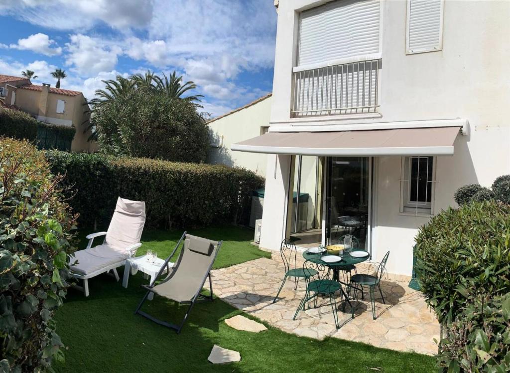 un patio avec des chaises et une table devant une maison dans l'établissement Résidence Port Soleil Bâtiment B1 - Appartement rez-de-chaussée 2 pièces - 2 pers - PORT SOLEIL MAE-1941, au Cap d'Agde