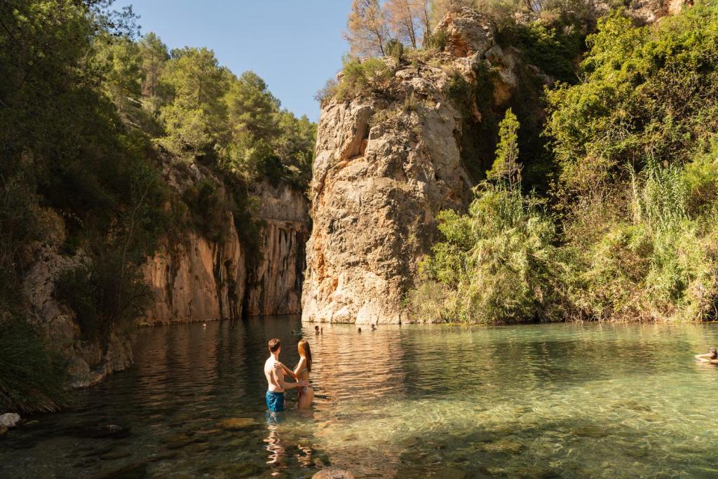 dos personas de pie en el agua en un río en Hotel Xauen, en Montanejos
