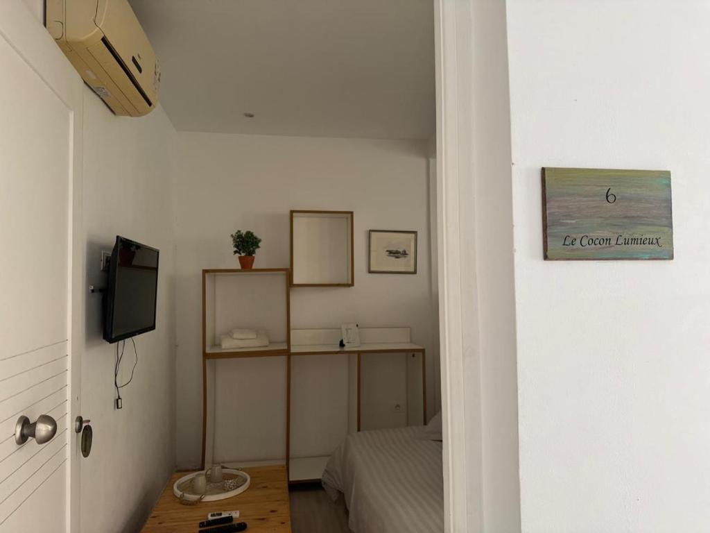 Una pequeña habitación con una cama y un televisor. en Le cocon lumineux, en Sfax