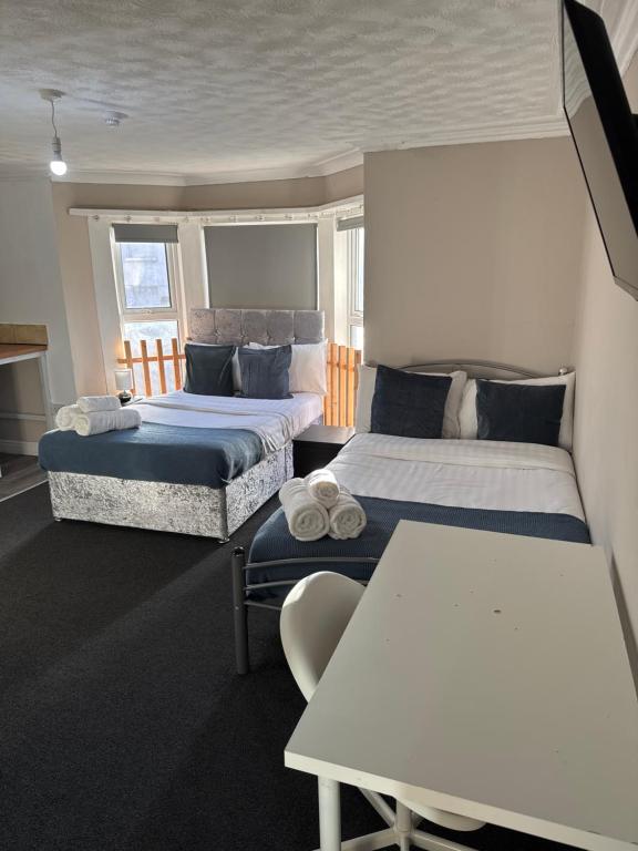 a hotel room with two beds and a table at Newstead En-suite Studios in Nottingham
