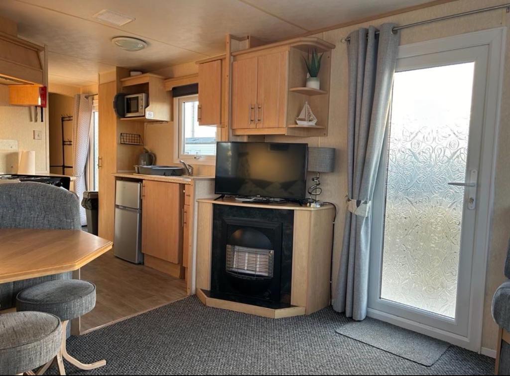 eine kleine Küche mit einem Wohnzimmer mit einem Herd in der Unterkunft Promenade park 8 Berth caravan next to the beach entrance, WIFI included in Ingoldmells