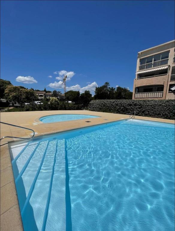 une piscine avec de l'eau bleue devant un immeuble dans l'établissement Charmant 2P entièrement rénové , Piscine , 1 km de la plage, à Sainte-Maxime