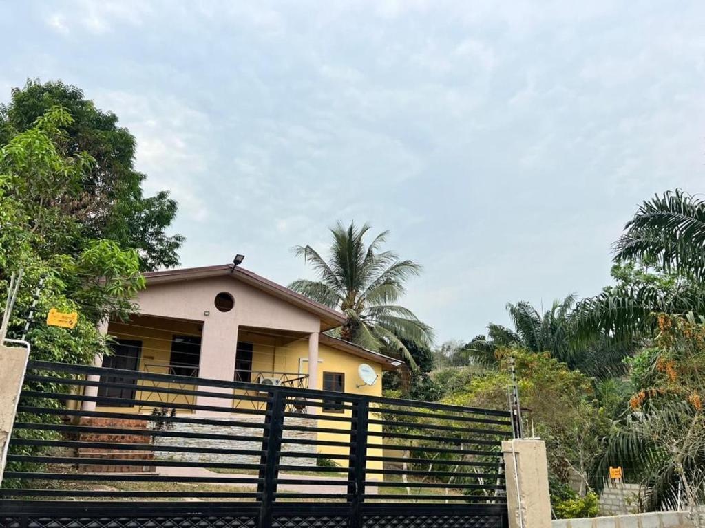 a yellow house with a fence in front of it at Mi Casa, Your Cozy Stay in Koforidua