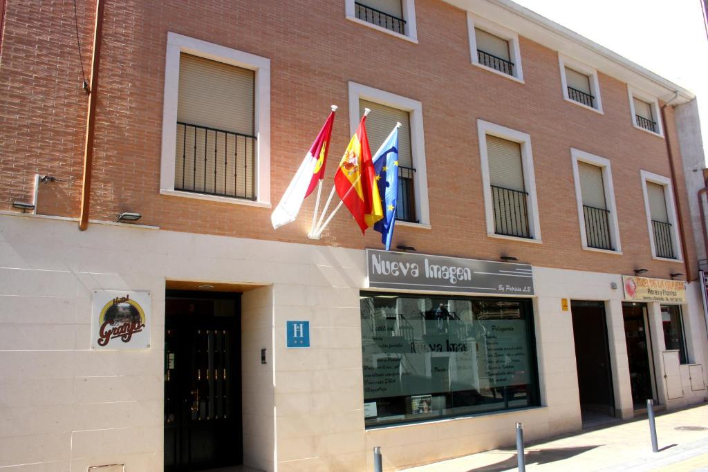 un edificio con banderas a un lado. en Hostal La Granja en Yunquera de Henares