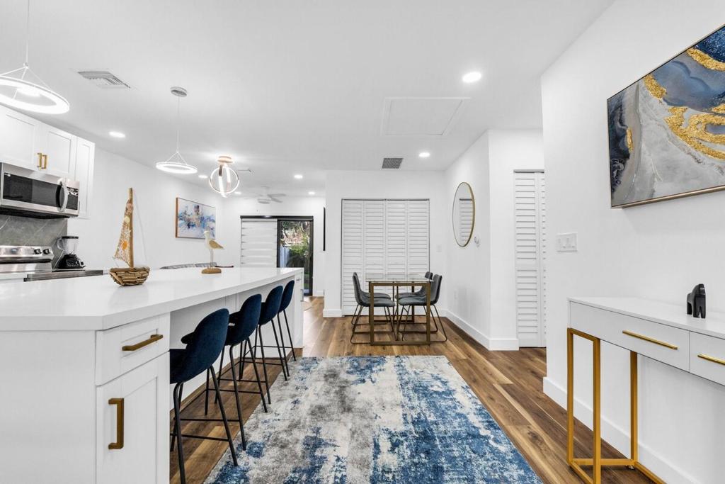 a kitchen with white cabinets and blue bar stools at Modern Home with large private yard - Next to downtown & beach & airport - Pet friendly in Fort Lauderdale