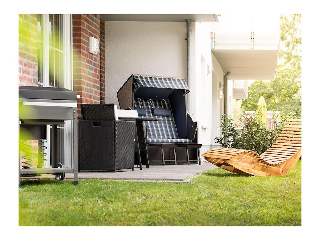 a patio with chairs and a table on the grass at Holiday apartment by the lake in Bad Zwischenahn