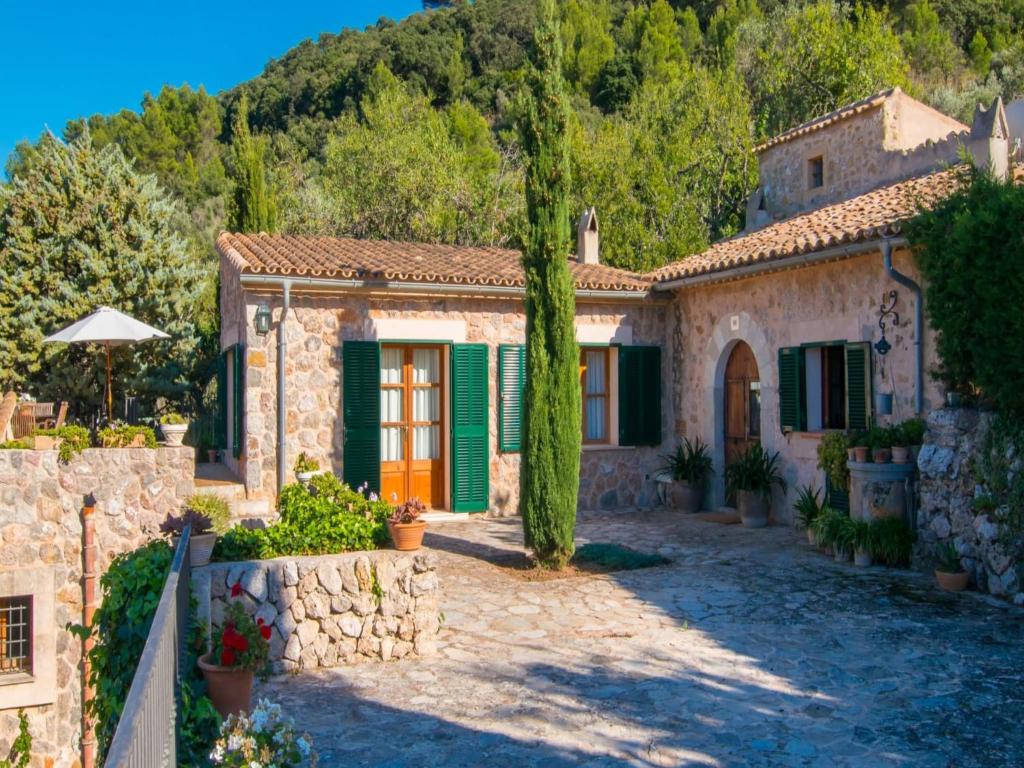 een stenen huis met een oranje deur en groene luiken bij Son Beltran villa with Pool in Valldemossa