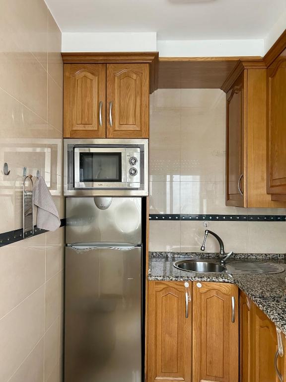 cocina con nevera de acero inoxidable y fregadero en Apartamento Aqua Marina, en O Grove