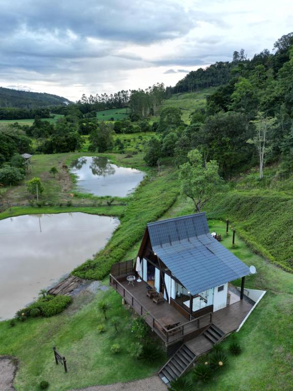 a house with a solar roof next to a lake at Chale Bouganville Ituporanga JACUZZI in Ituporanga