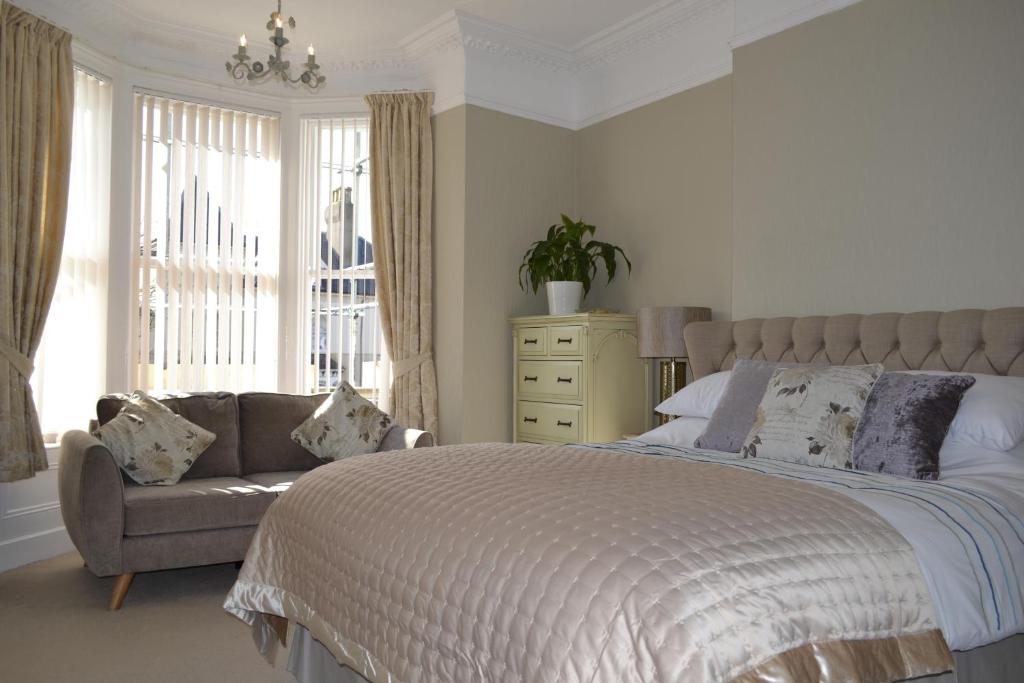 a bedroom with a bed and a couch and a window at The Westbourne Guest House in Llandudno