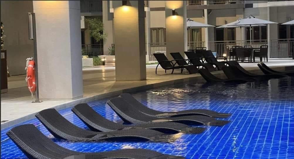 a swimming pool with black lounge chairs in a building at LuxeRN Suite at S Residences in Manila