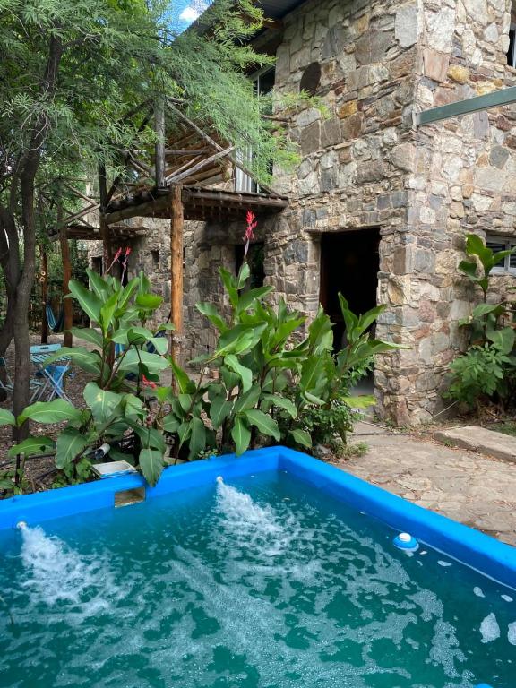 a blue swimming pool in front of a stone building at Cabañas Cuyum in El Volcán