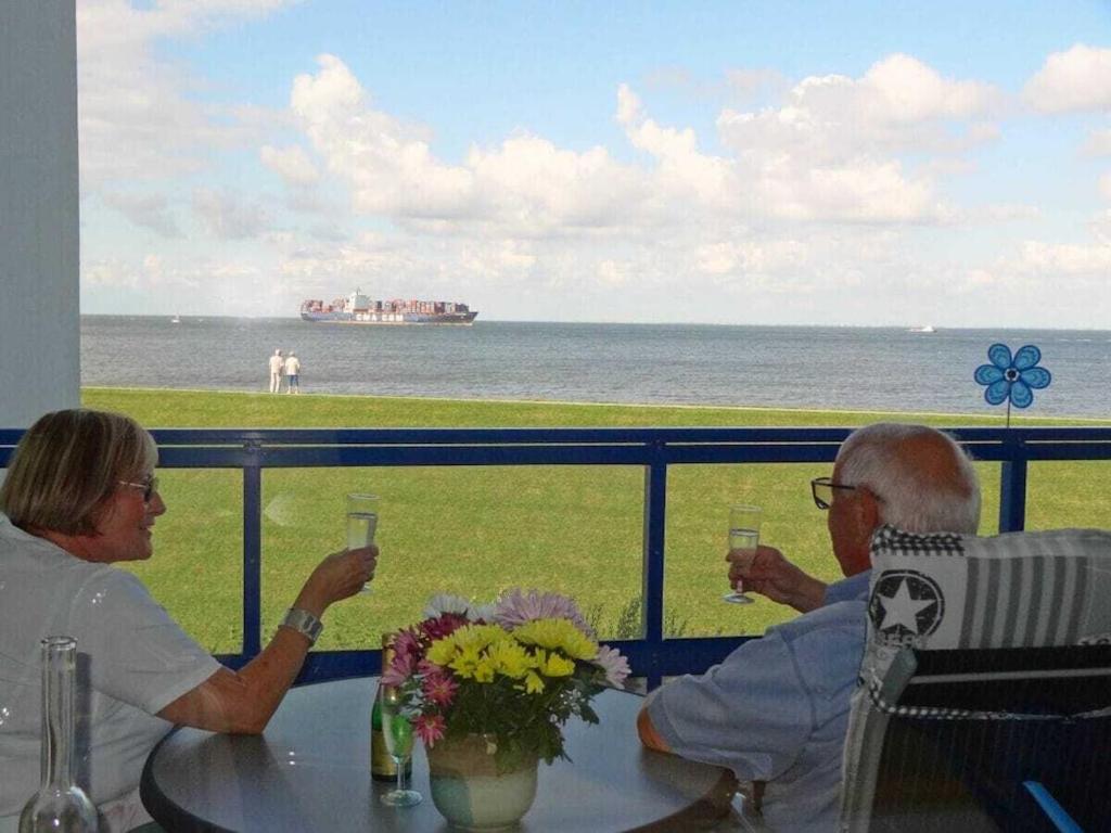 Un hombre y una mujer sentados en una mesa con copas de vino. en my, your, our holiday apartment, en Cuxhaven