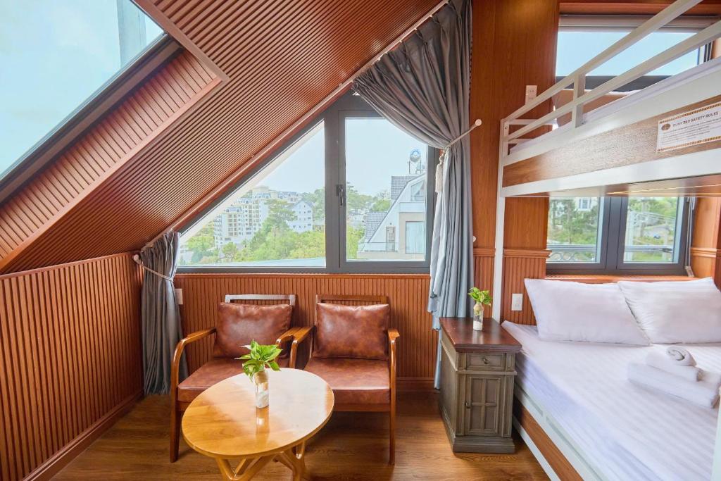 una camera da letto con un letto, un tavolo e delle sedie di Lotus Hotel Đà Lạt a Khu Chi Lăng