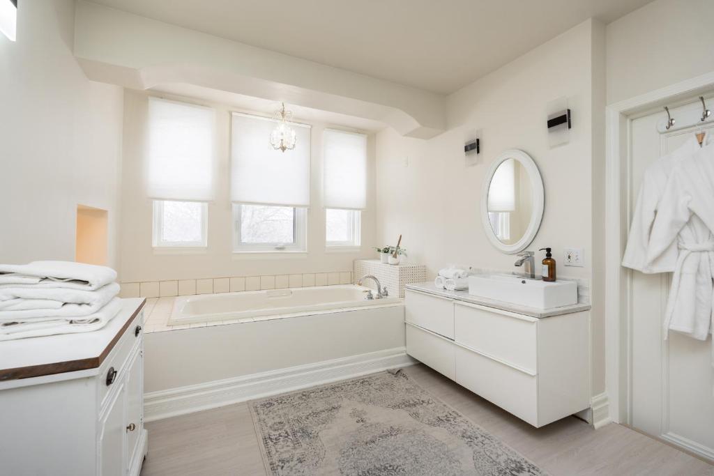 a white bathroom with a tub and a sink and a mirror at No. 5 East in Winnipeg