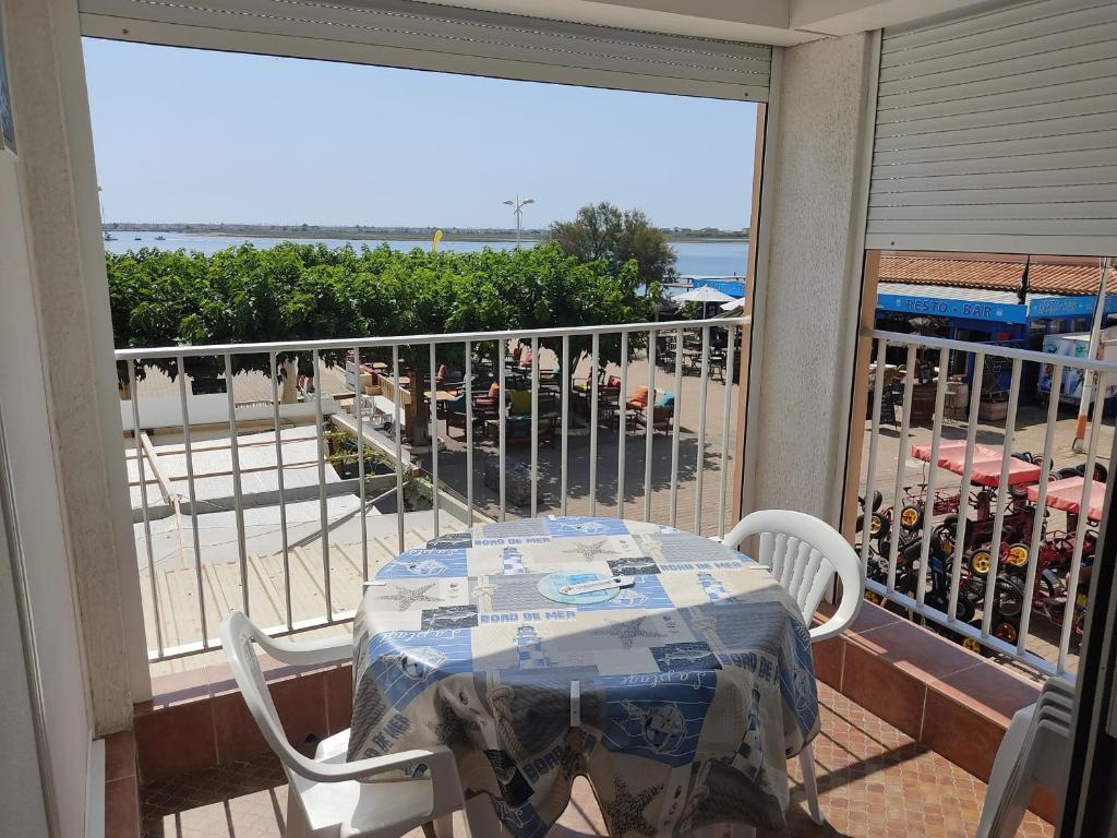 une table et des chaises sur un balcon avec vue sur la plage dans l'établissement Gruissan - Appartement climatisé - 6 pers - Parking - Plage à 50m - FR-1-796-51, à Gruissan