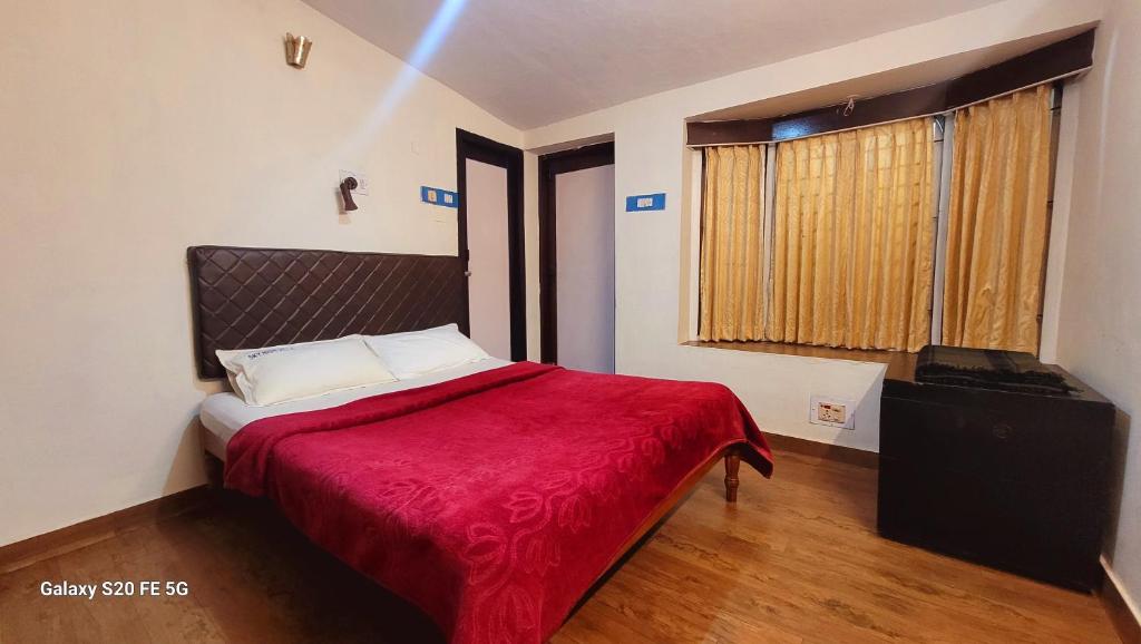 a bedroom with a bed with a red blanket at Green Woods Homestay in Kodaikānāl