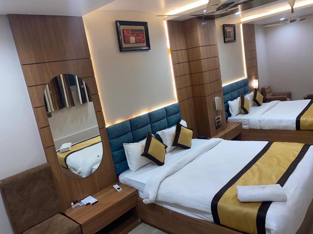 a hotel room with two beds and a mirror at Hotel New Grand in Deoghar