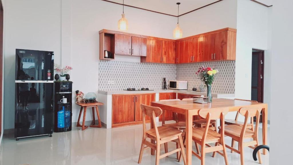 a kitchen with a wooden table and chairs and a refrigerator at Aksamala Villa Echobeach Canggu in Canggu